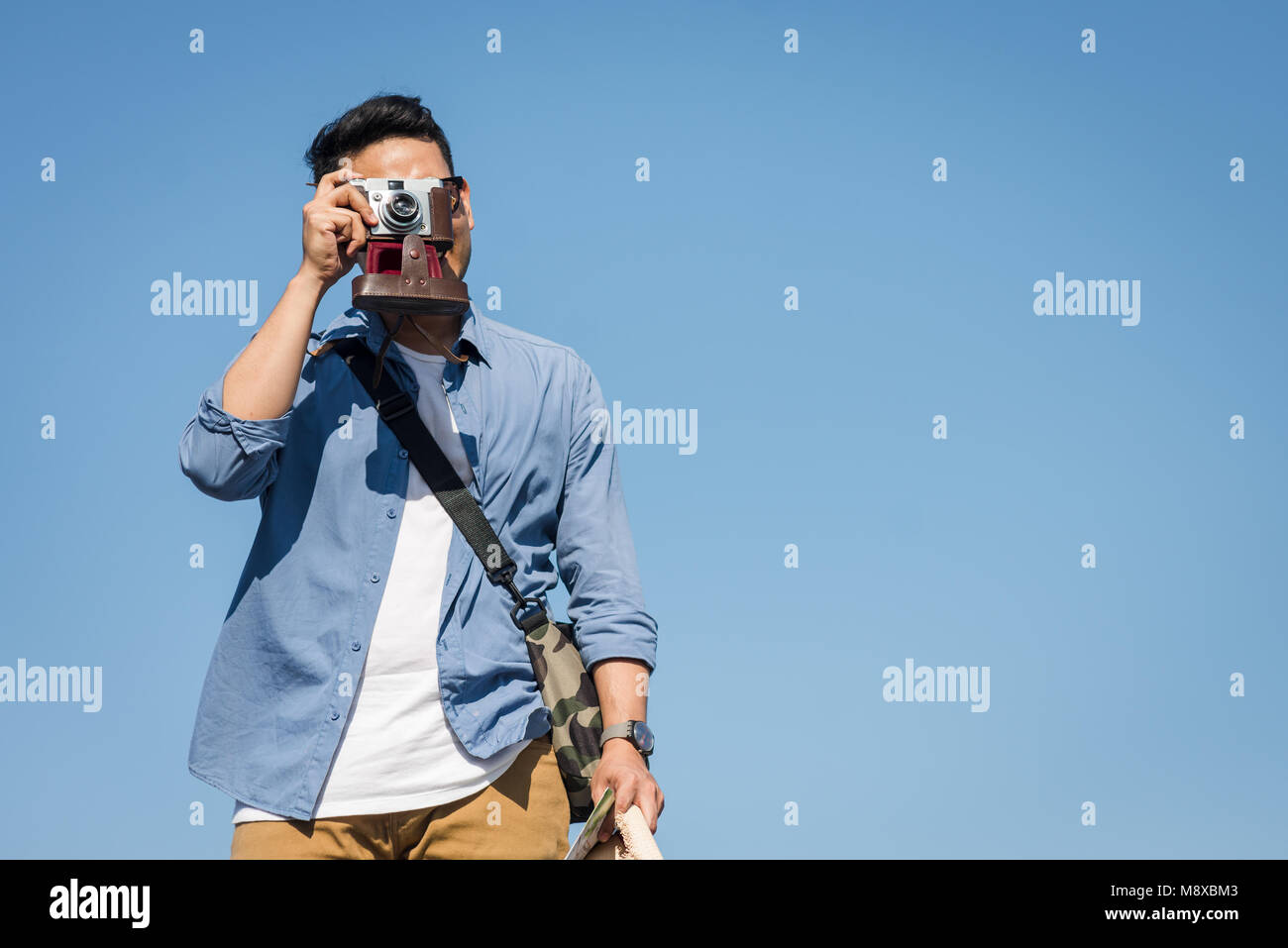 Happy Asian toursit taking vintage camera  with blue sky in sunny day. Stock Photo