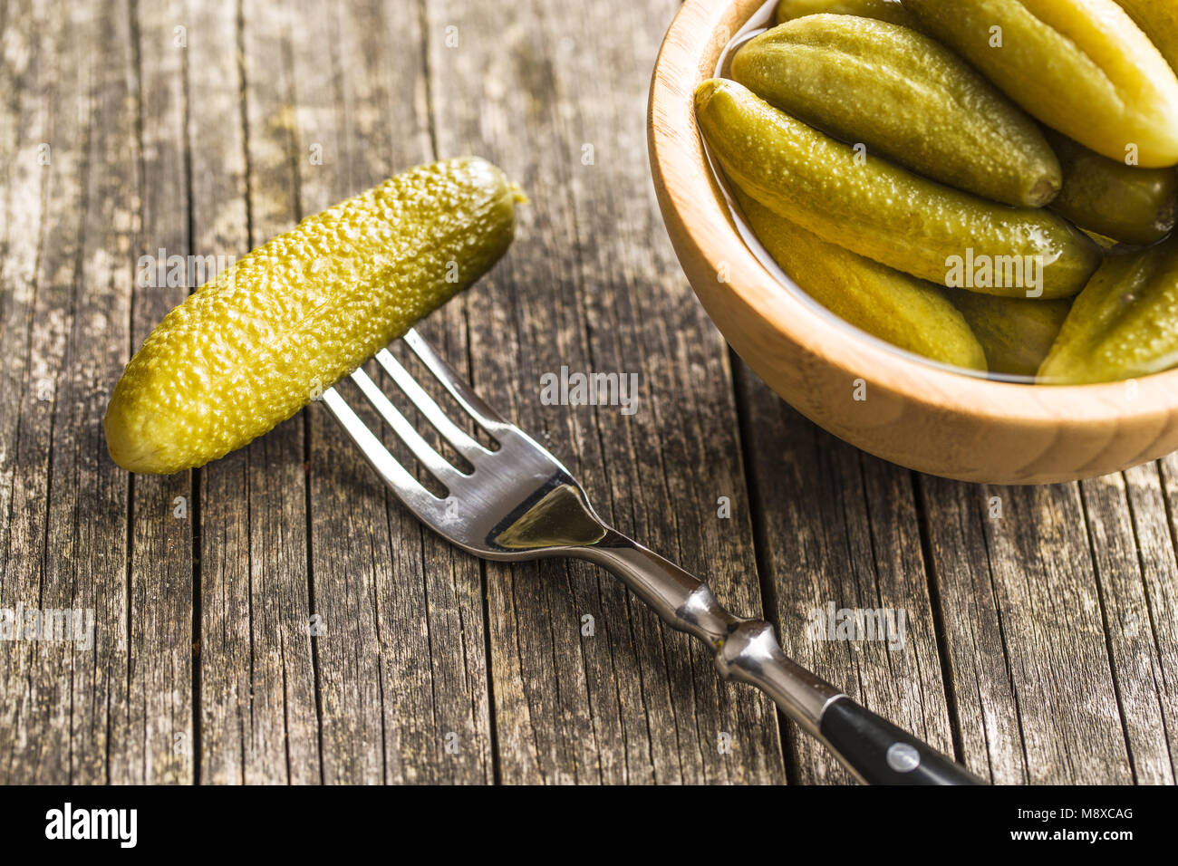 Pickles in bowl. Tasty preserved cucumbers on old kitchen table Stock