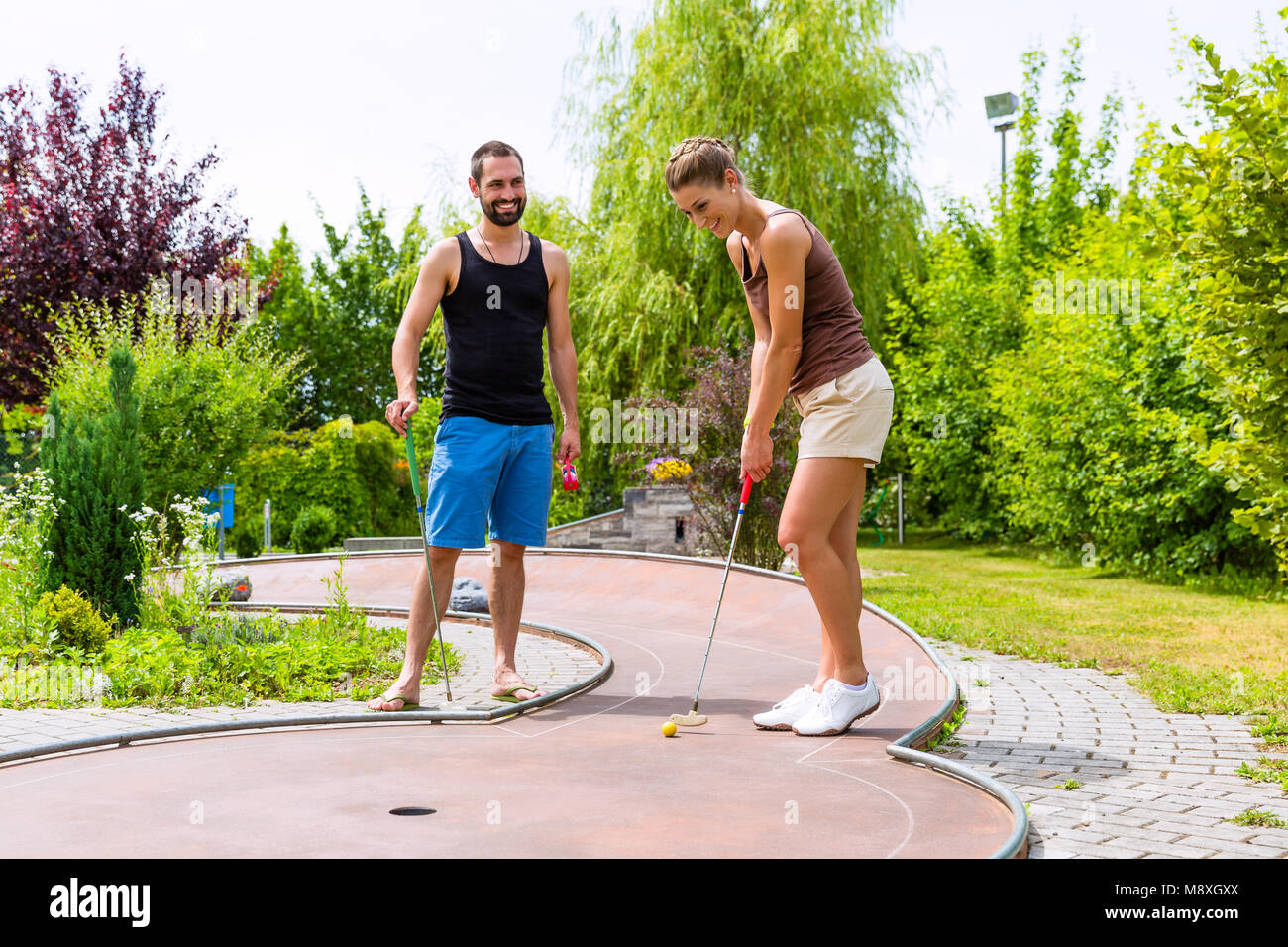 Couple playing together miniature golf outdoors Stock Photo