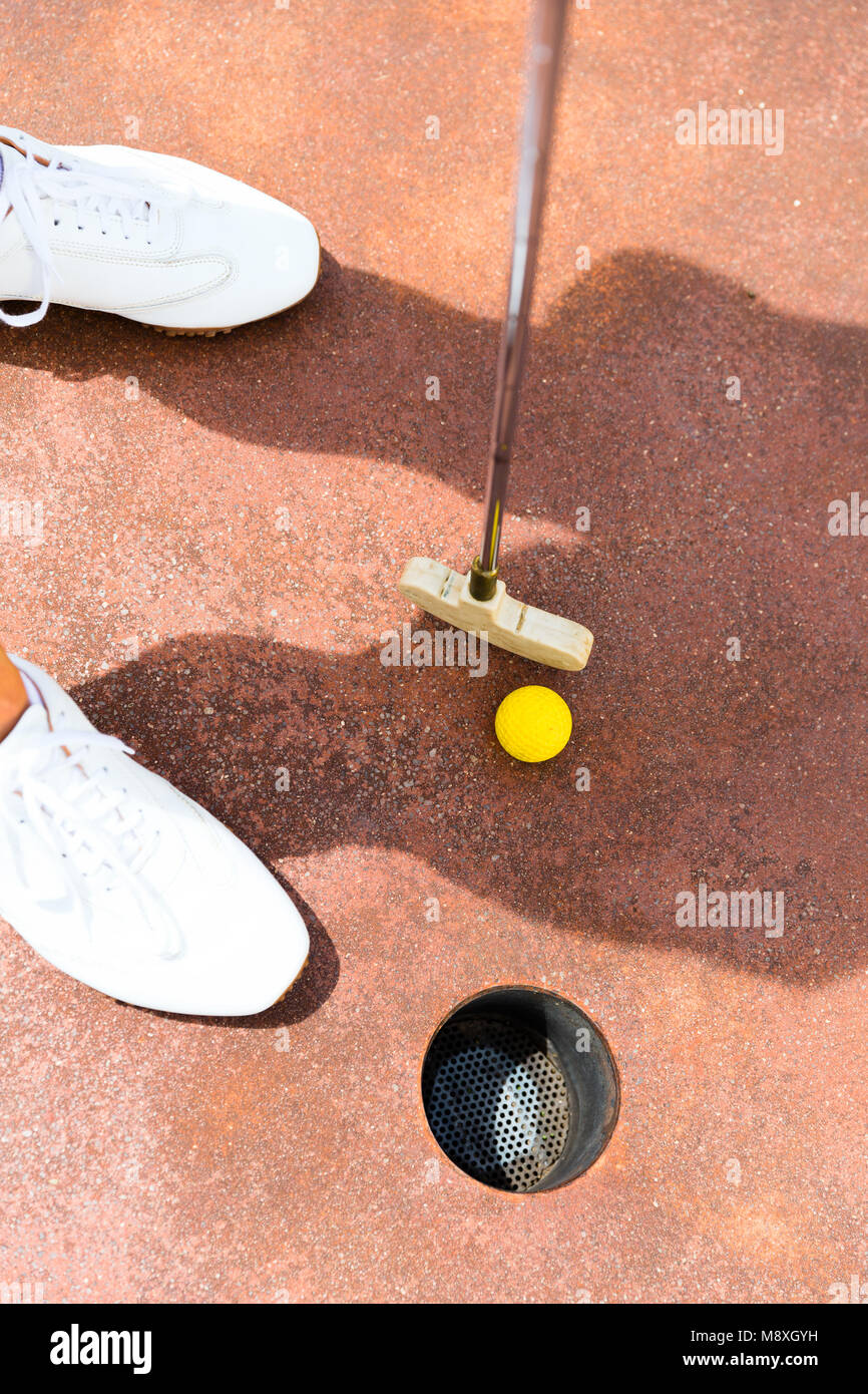 Woman playing miniature golf, holing in Stock Photo