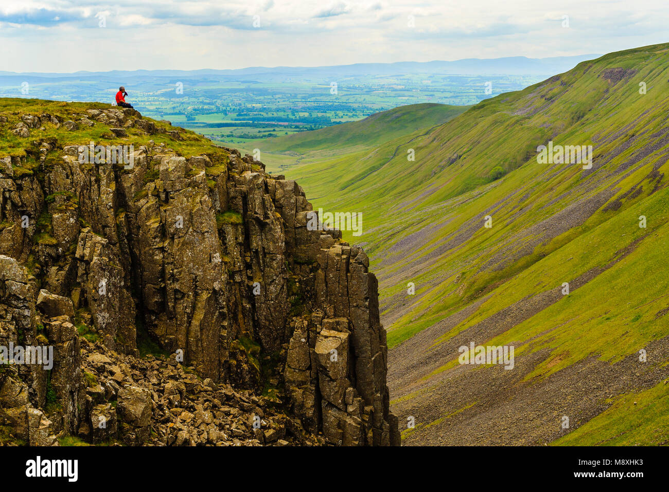 Walker takes a break overlooking High Cup a dramatic landscape feature in the North Pennines above the Eden Valley Cumbria Stock Photo