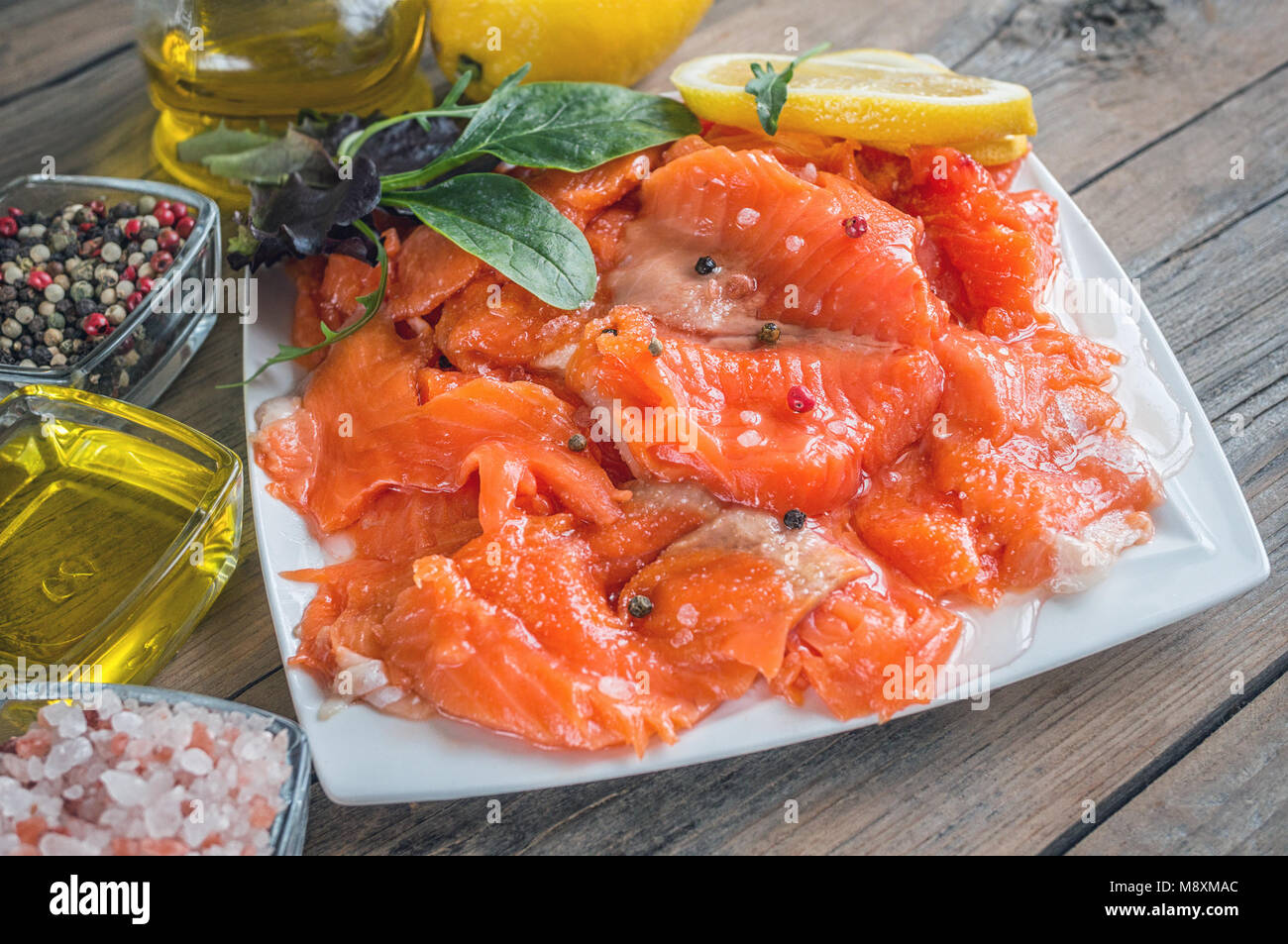 Raw pickled trout fillet and salmon pieces in a white plate. Wooden background. Healthy tasty food. Stock Photo