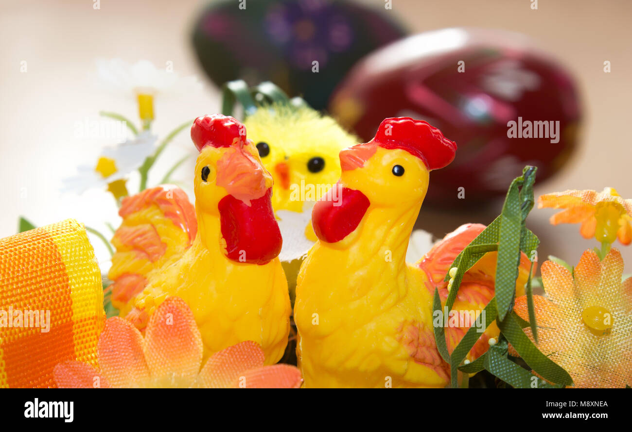 Easter decorations. In the foreground there are two hens behind them is a chicken and in the background is a painted egg. Stock Photo