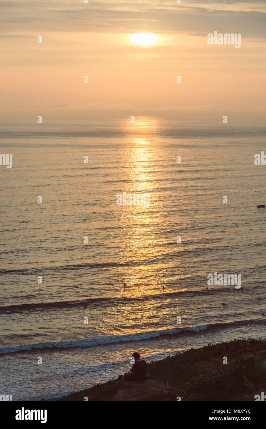 Man sitting at the foot of the sea watching the sunset Stock Photo - Alamy
