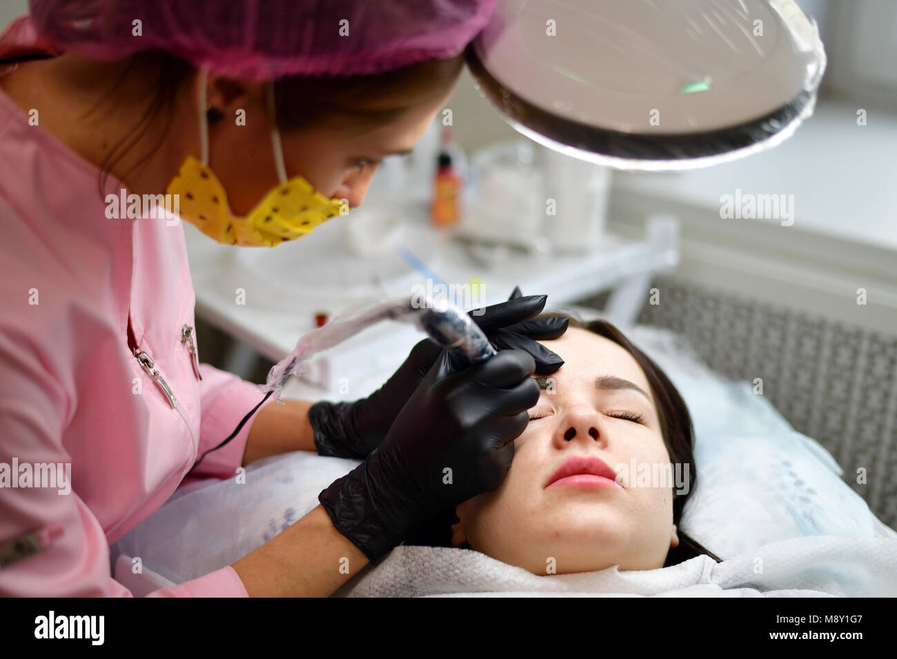 cosmetologist does hardware skin care for girl's face Stock Photo