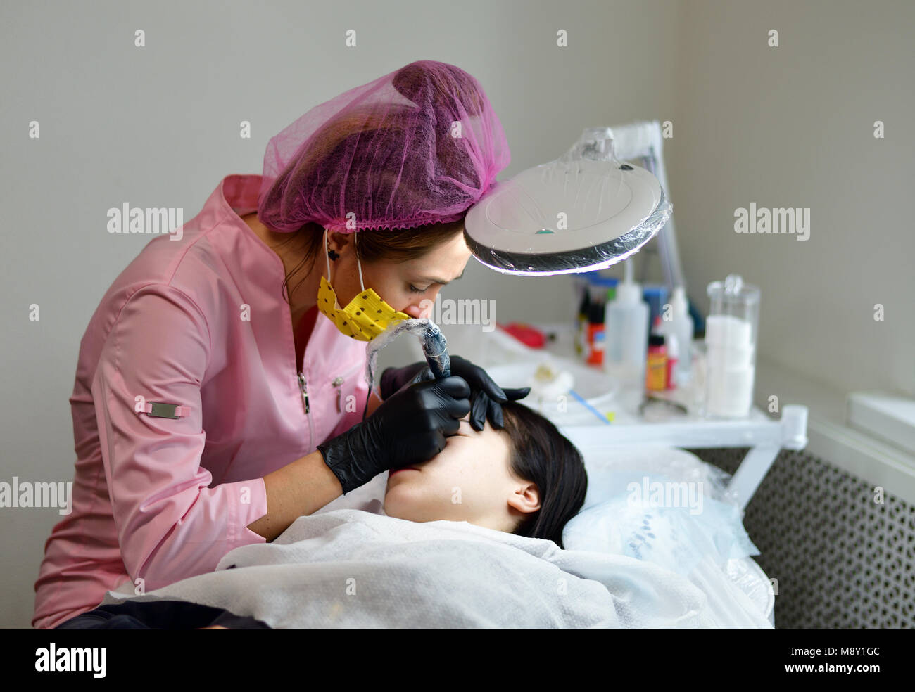 cosmetologist does hardware skin care for girl's face Stock Photo