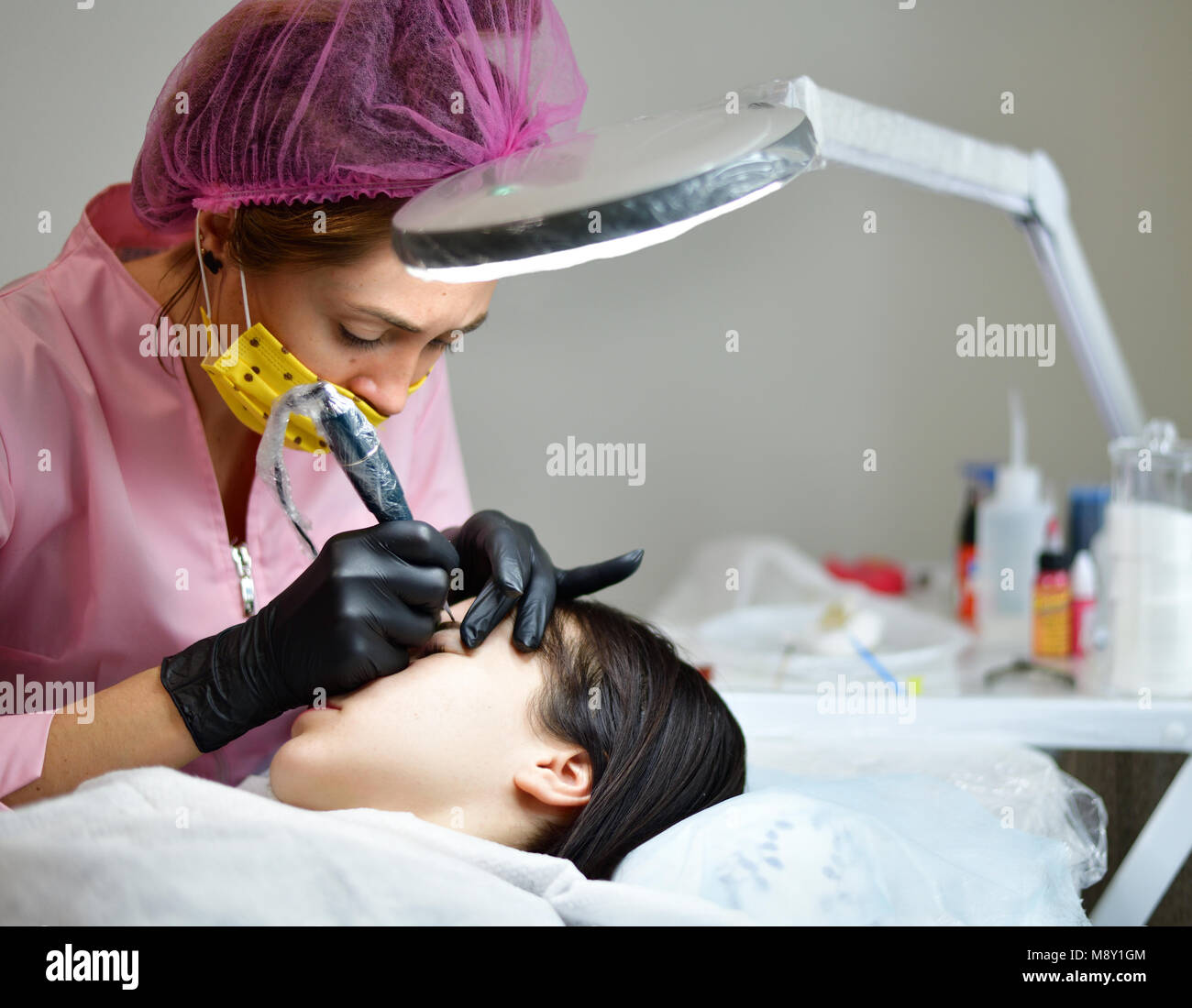 cosmetologist does hardware skin care for girl's face Stock Photo
