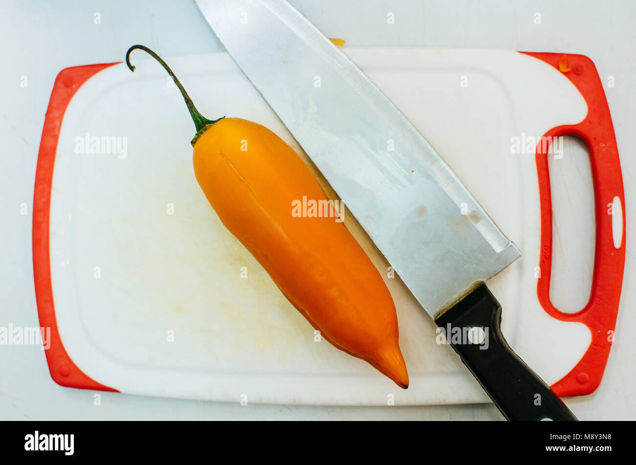 Chili pepper and a knife on a chopping board Stock Photo - Alamy