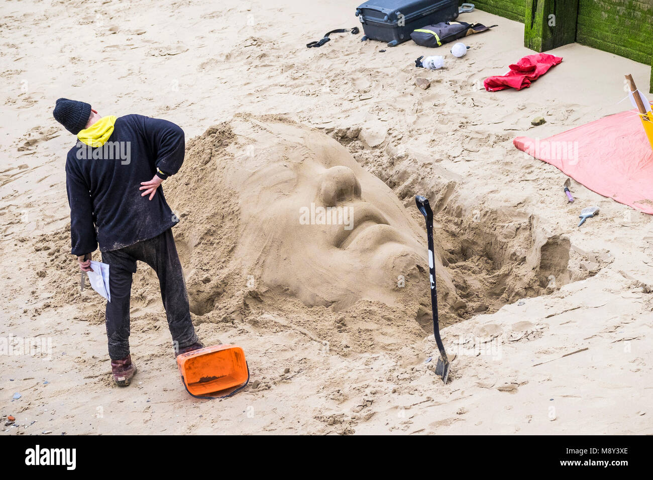 A sculptor creating a sand sculpture on the foreshore of the River Thames on the South Bank in London. Stock Photo
