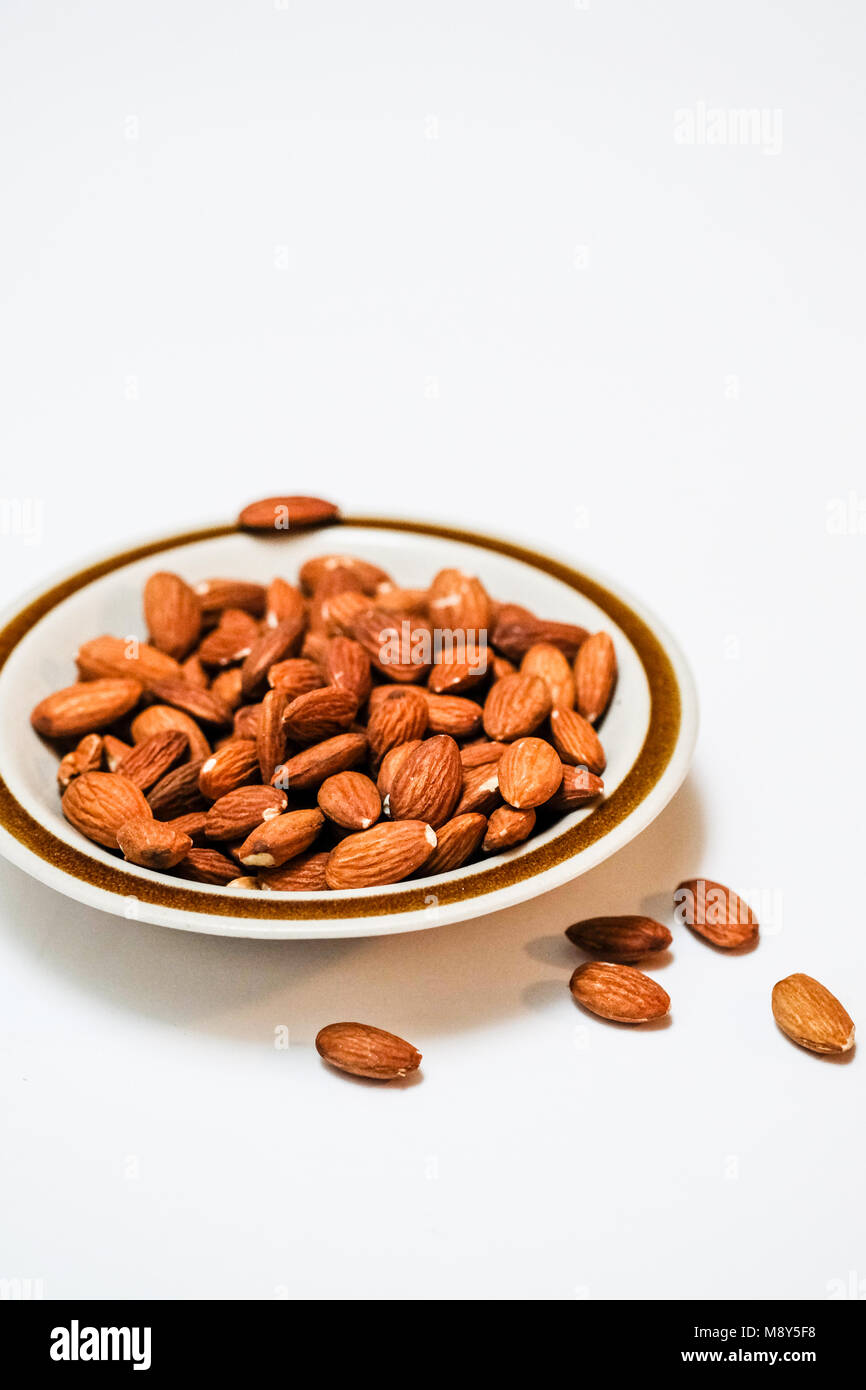 A small plate of almonds plain white background Stock Photo