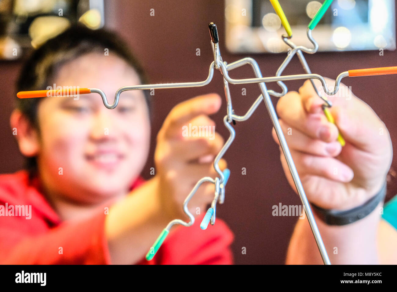 An autistic boy plays magnetic balancing sticks with a counselor at a game room Stock Photo