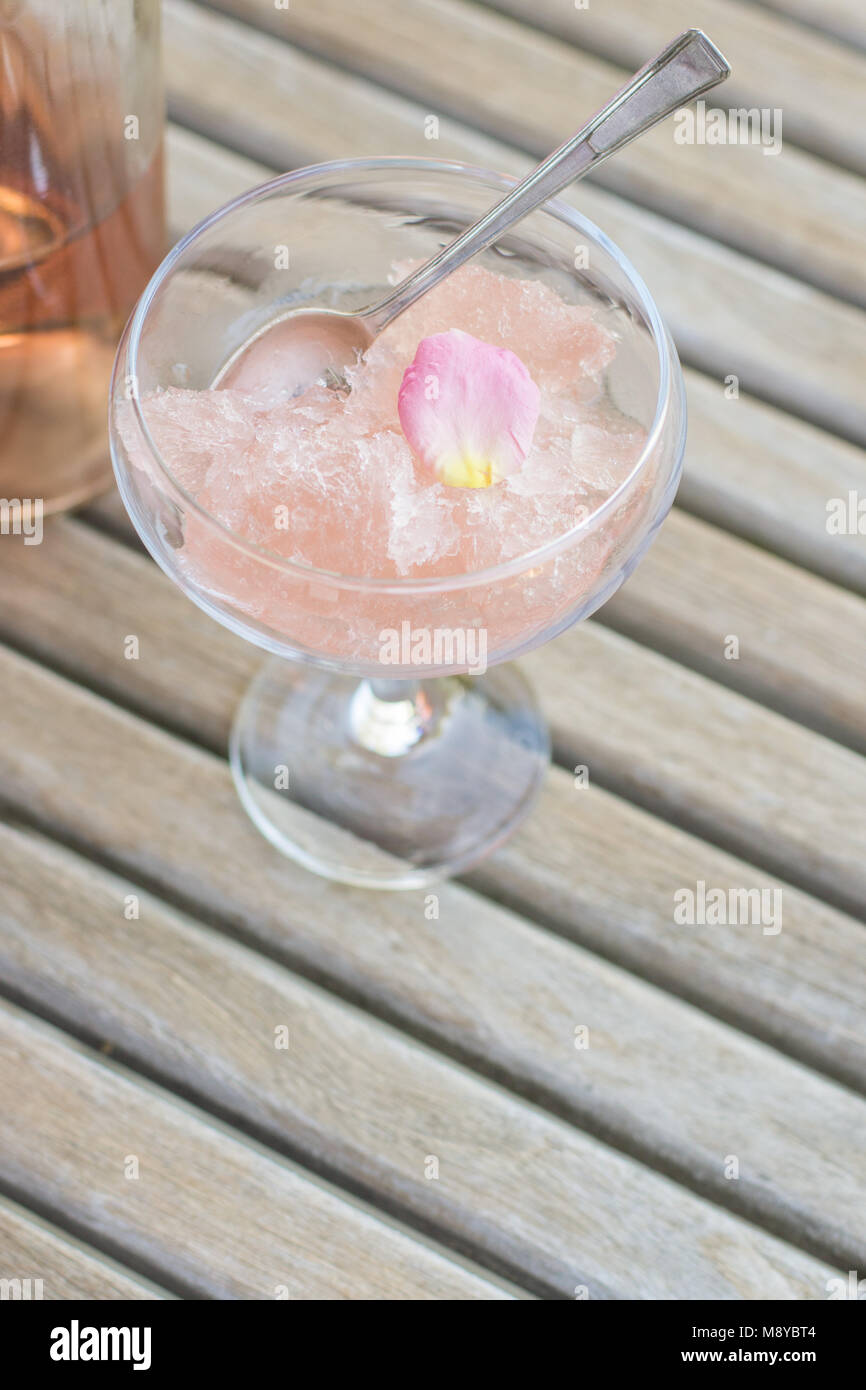 Frozen rose wine in a dessert glass with a spoon and organic rose