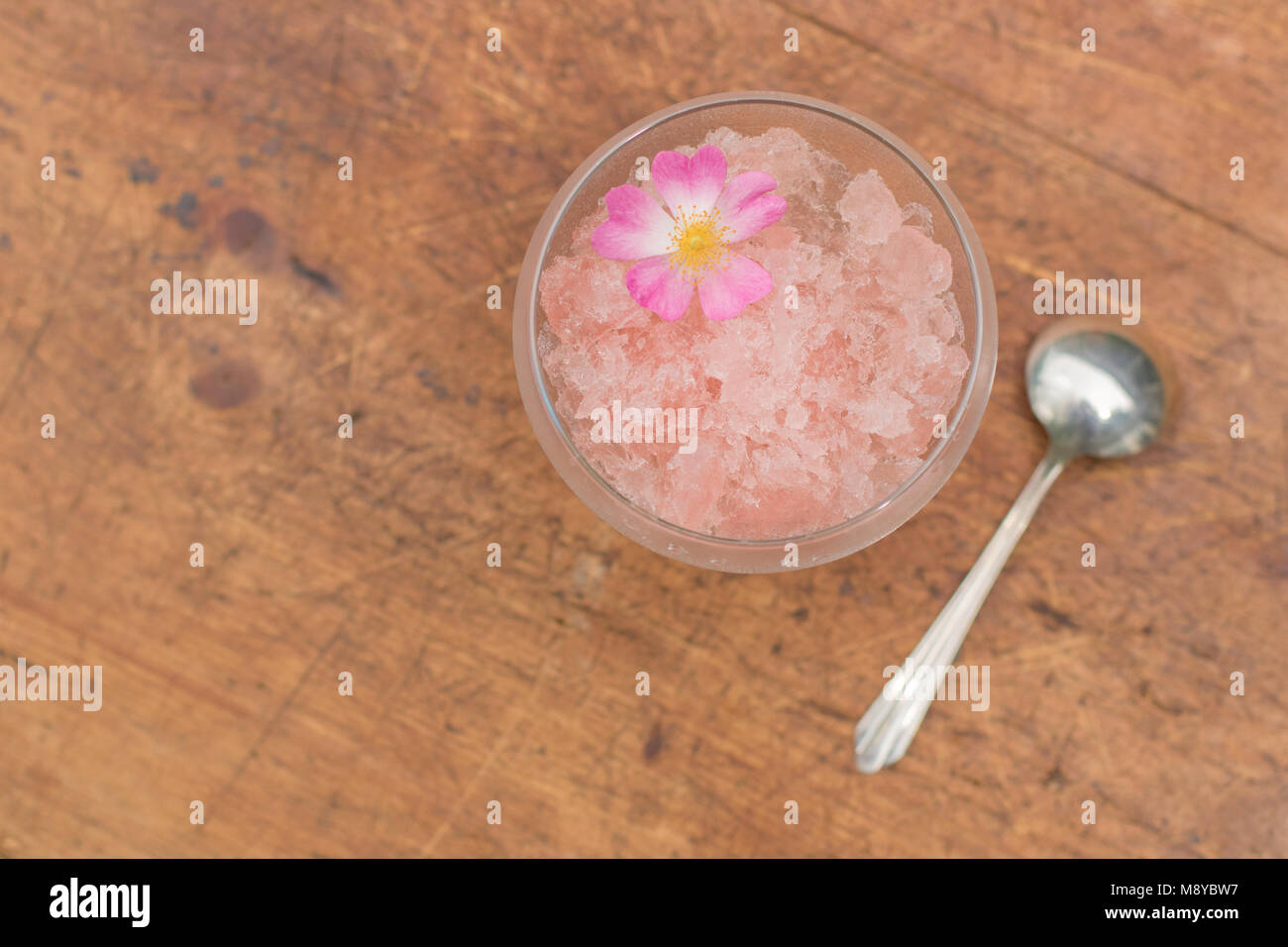 Frozen rose wine in a dessert glass with a spoon and organic rose