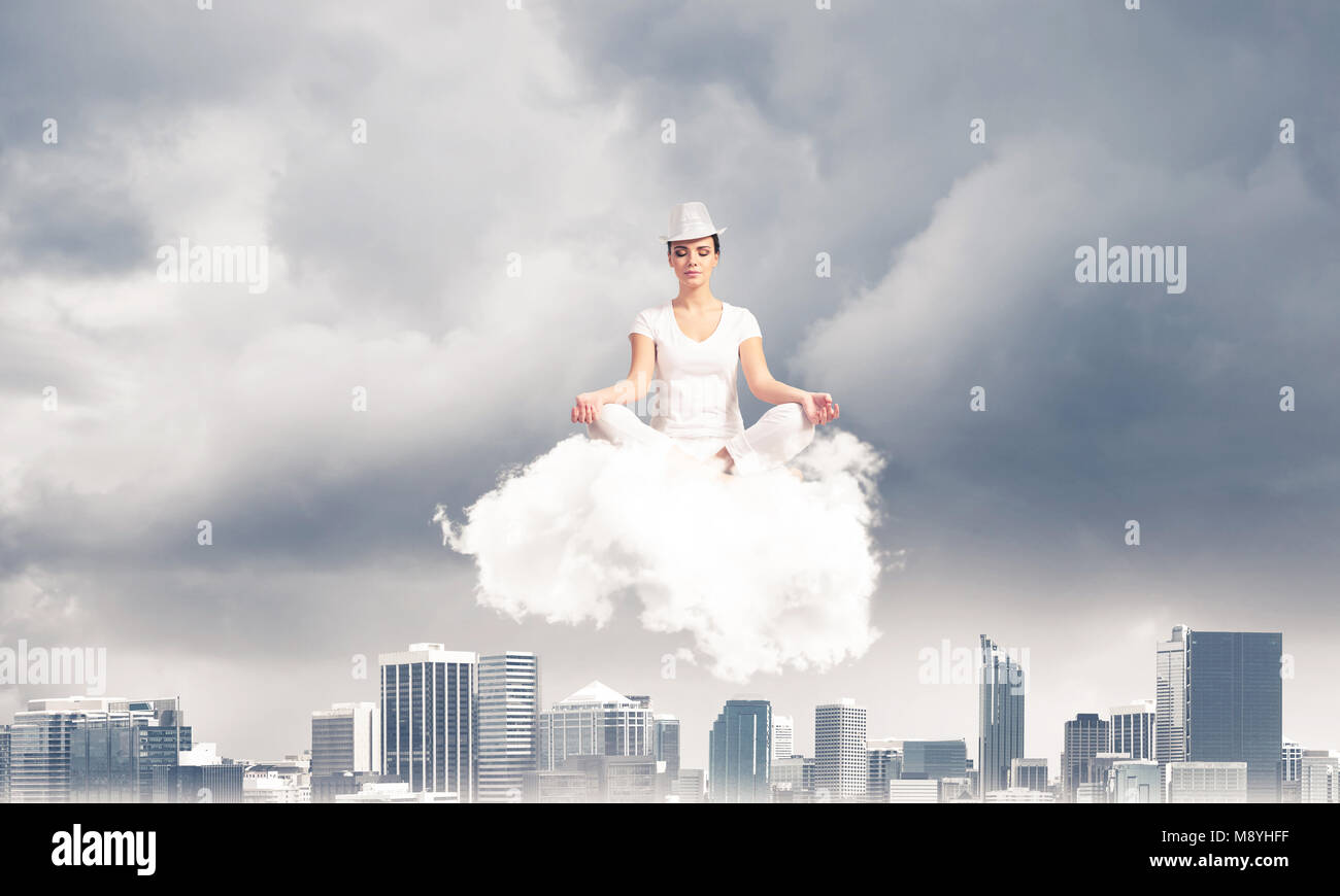 Woman in white clothing keeping eyes closed and looking concentrated ...