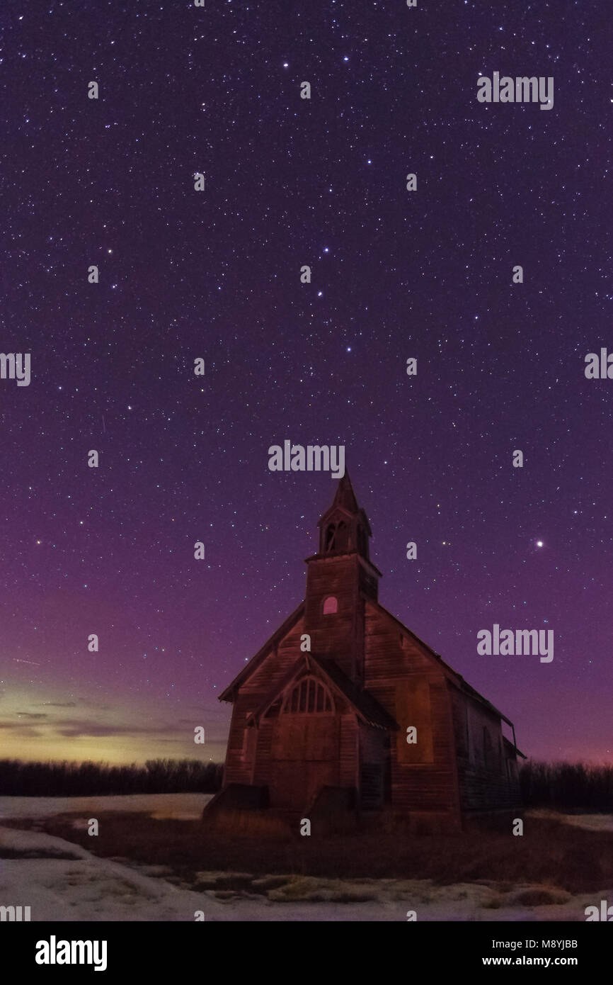 A purple aurora sky and stars over an abandoned church in near Stewart Valley in southwest Saskatchewan in the winter Stock Photo