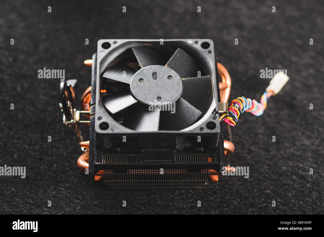 CPU heat sinker from a PC. Copper heatsinker with a fan for cooling the processor. Isolated on a dark background. Top view. Stock Photo