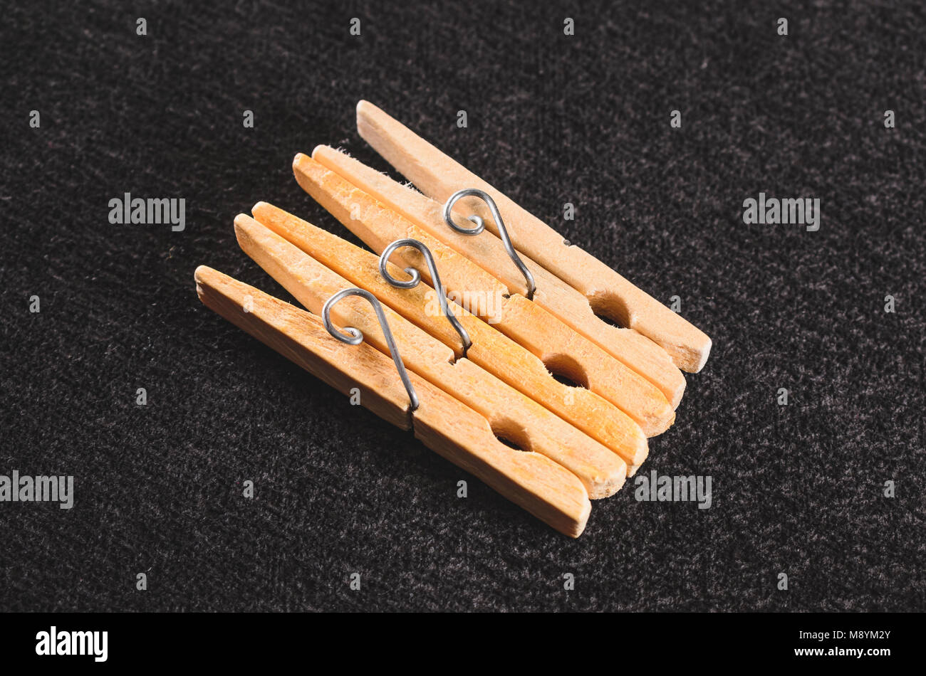 Three wooden clothespin clamps isolated on a dark textured background
