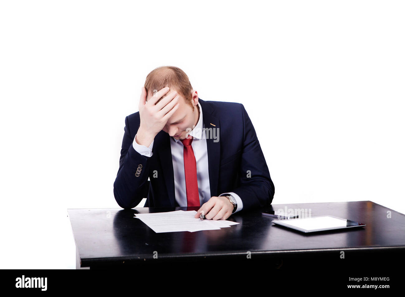 Sad engineer, reads a contract, looks at documents, putting his right hand to his head. Stock Photo