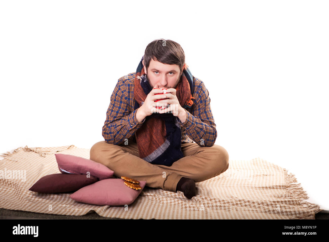 cold man with flu wrapped in a warm blanket, holding a mug. Stock Photo