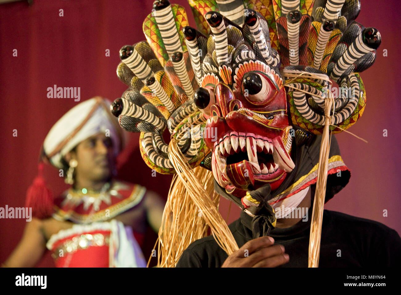 Traditional Sri Lankan dancers and musicians at a display - in this image the dancer is wearing a Raksha Mask - Slow shutter speed so motion blur. Stock Photo