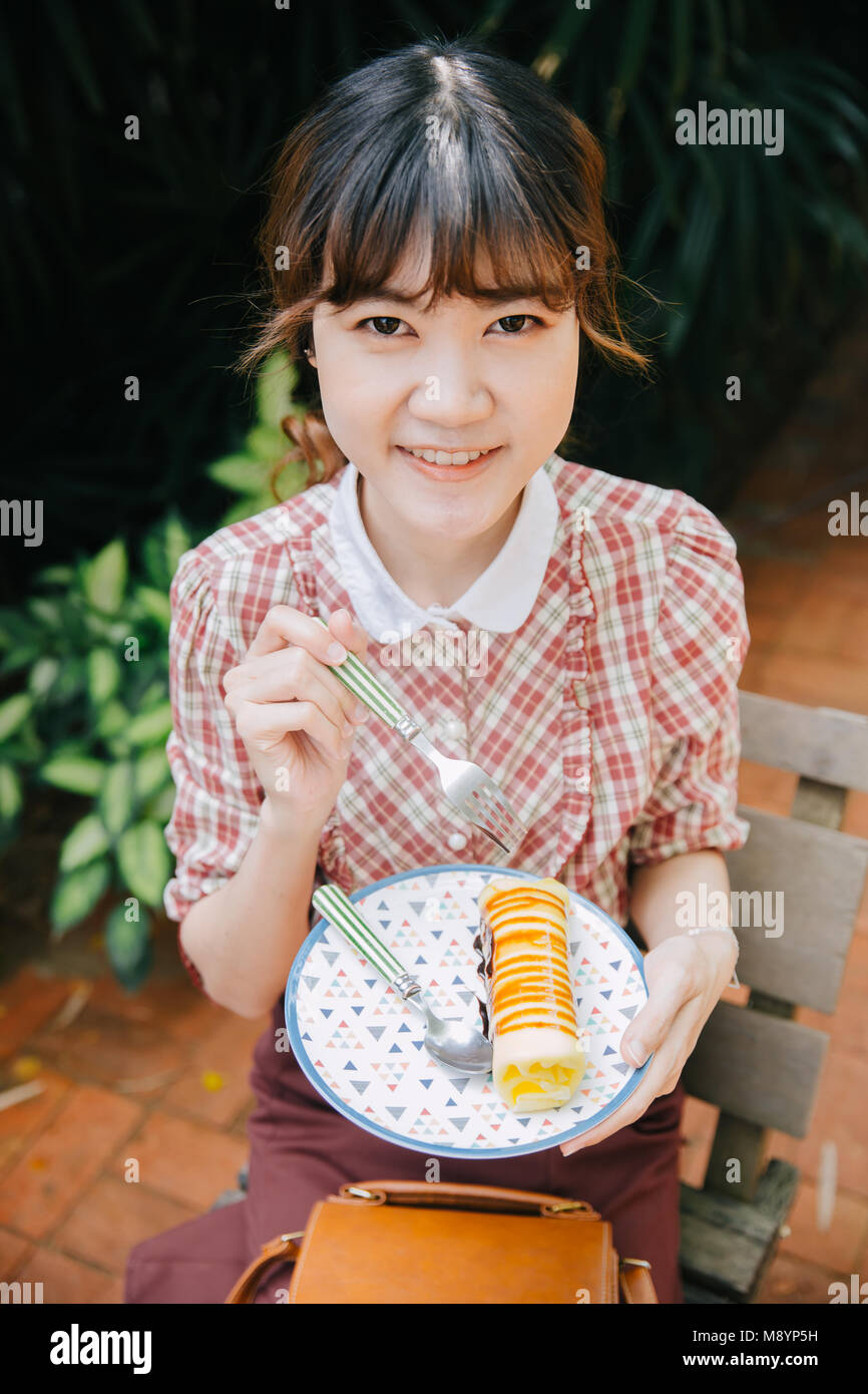 Asian Girl young teen hipster happy eating dessert cake roll Stock Photo