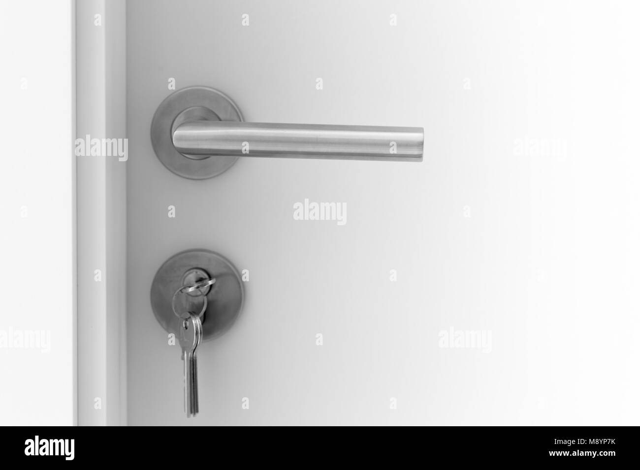 Closeup white Door handle metal with key to unlock or locking door Stock Photo