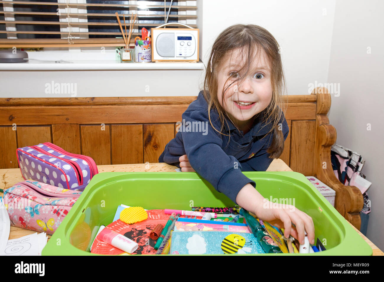 young girl at table picking out colouring pens Stock Photo