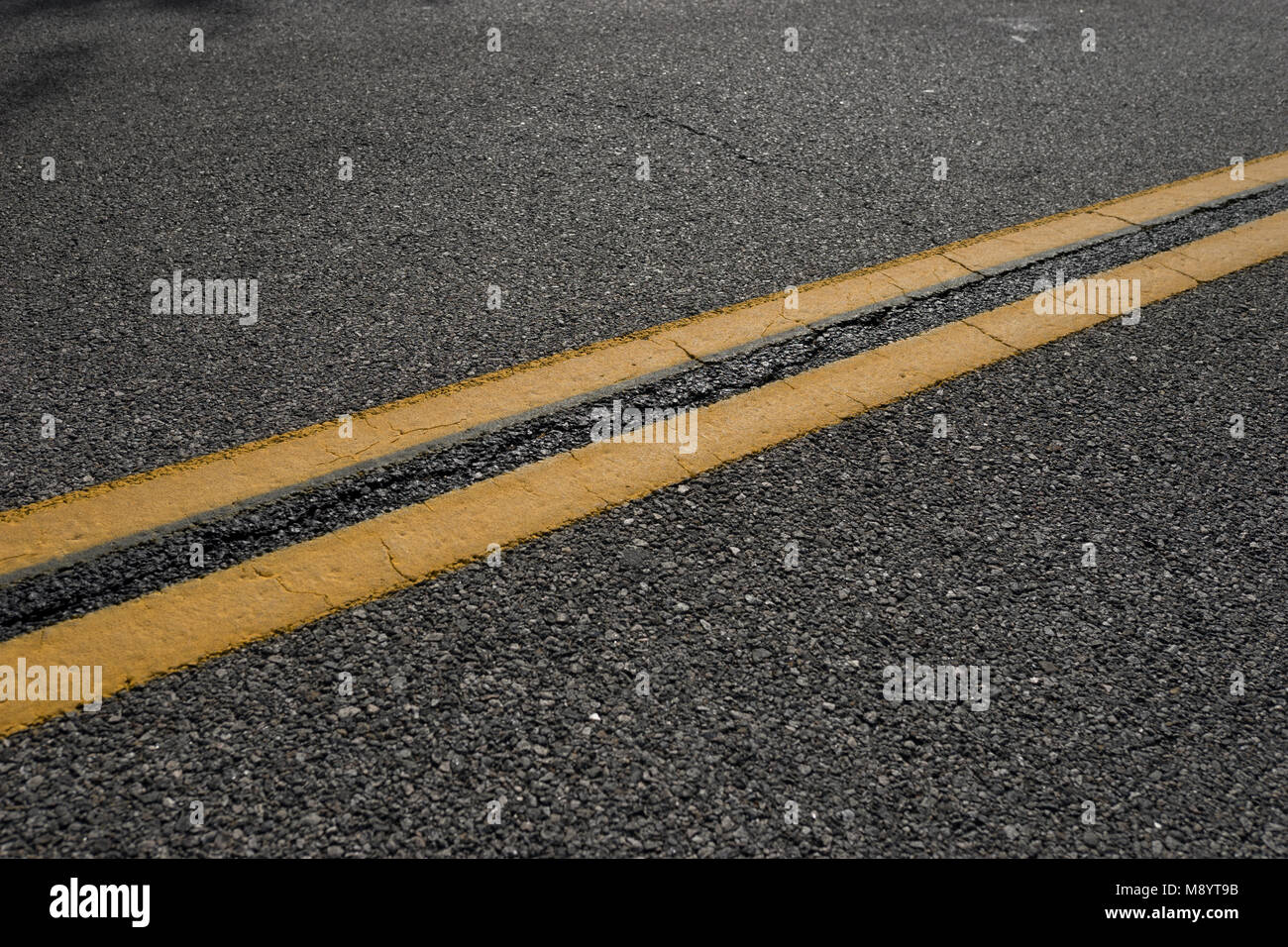 Line of double yellow paint marks the division of roadway on an asphalt