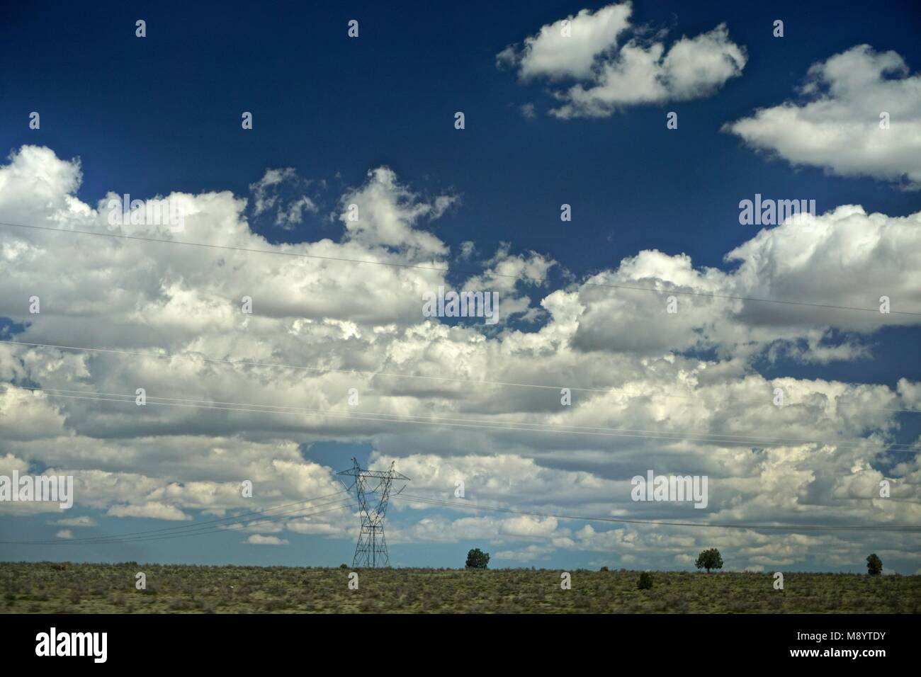 Coconino County, AZ, USA: Clouds in a deep blue sky over powerlines along State Highway 64 between the Grand Canyon and Williams, Arizona. Stock Photo