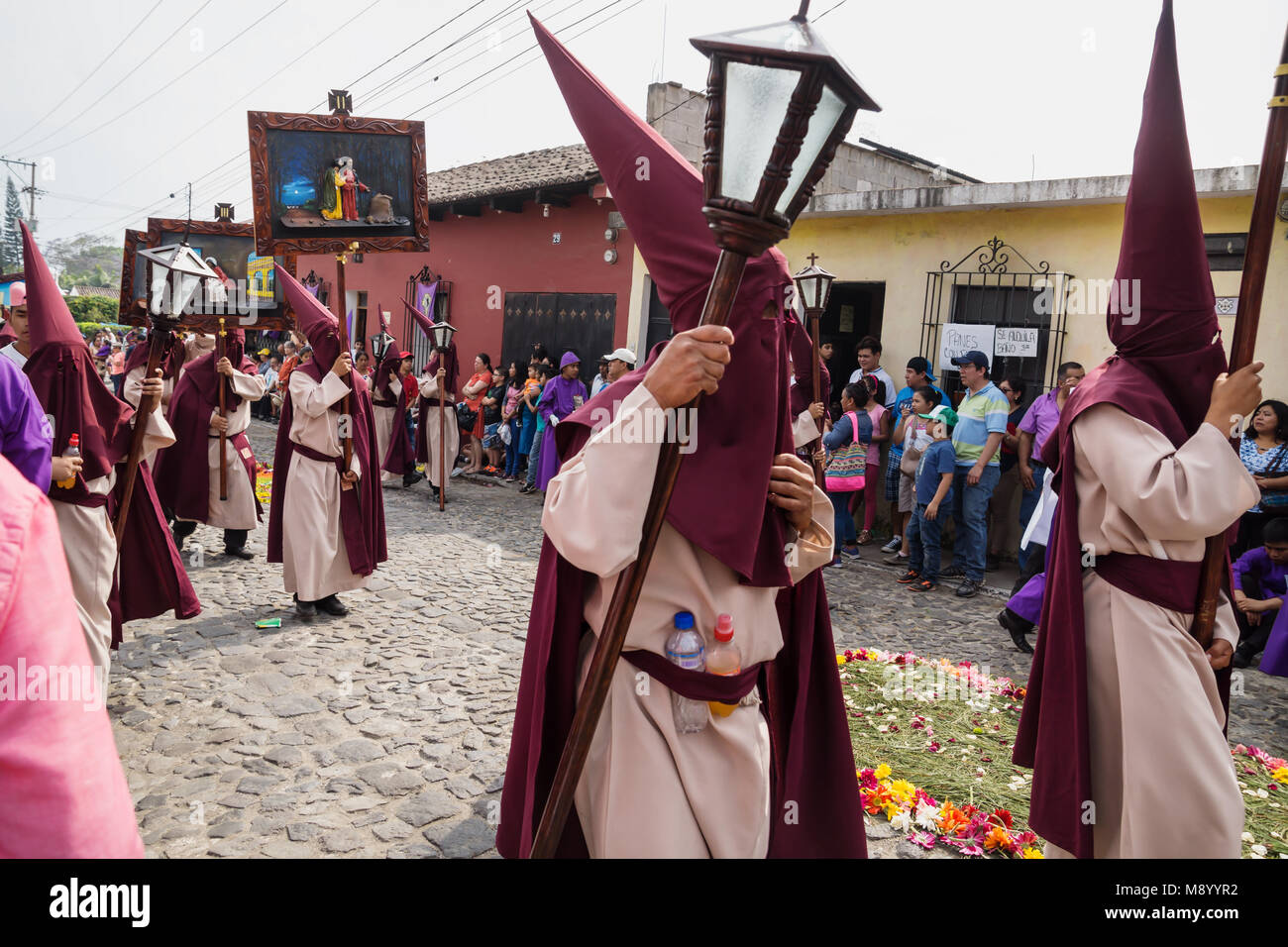 Antigua, Guatemala: March 18 2018: People with pointed hood costumes carrying paintings of the way of the cross at the procession of San Bartolome de  Stock Photo