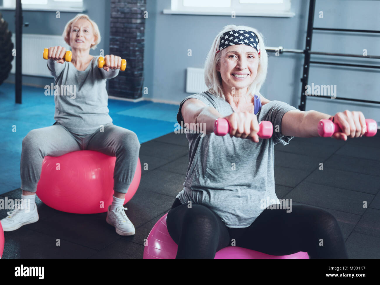 Radiant woman holding dumbbells while training at fitness club Stock Photo