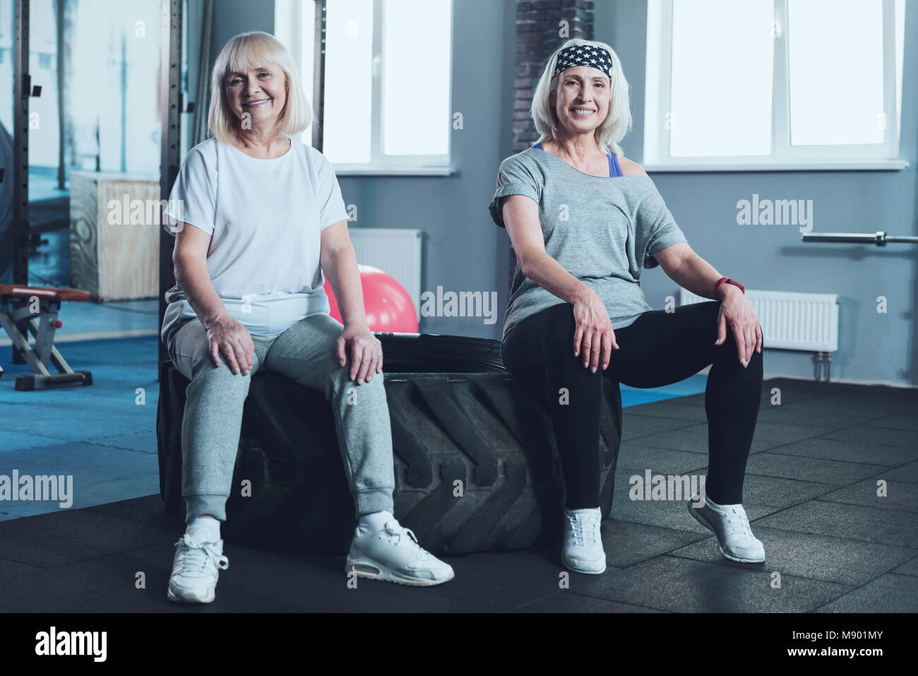 Pleasant retired ladies having rest on tire after training class Stock Photo
