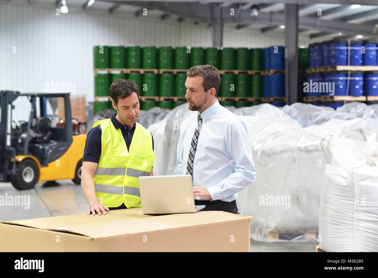 meeting of the manager and worker in the warehouse - forklift and interior of the industrial building Stock Photo