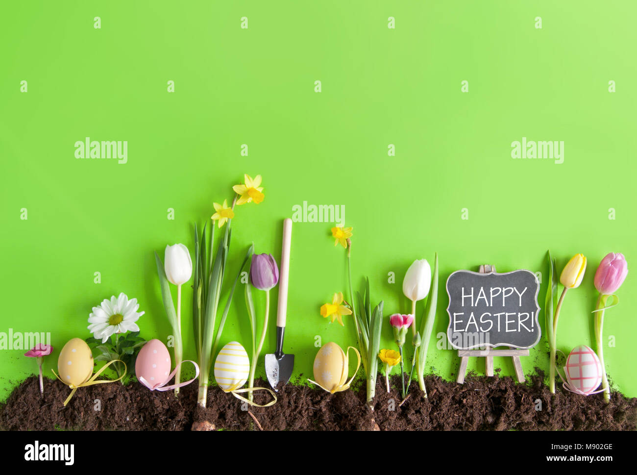 Happy easter message on a chalkboard on a flower bed background with