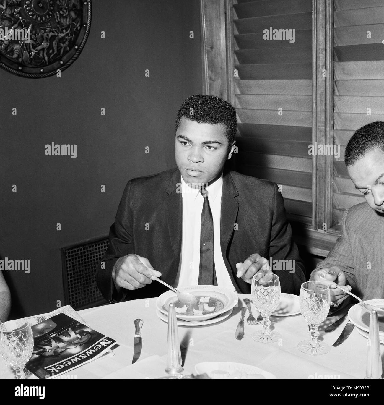 Cassius Clay (Pictured) having lunch in London before his trip to Scotland for an exhibition bout against fellow American Jimmy Ellis. However, his visit didn't go to plan after fans booed during the exhibition fight. The World Champion berated them saying: 'All booing must stop when the king's in the ring.' The visit had started on a positive note a few days earlier when Ali made a visit to Glasgow's Oakbank Hospital. He happily signed autographs for patients. 16th August 1965 Stock Photo