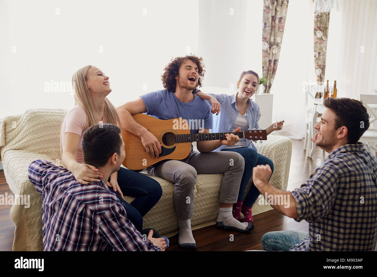 A group of friends with a guitar sing songs at a party indoor Stock Photo -  Alamy