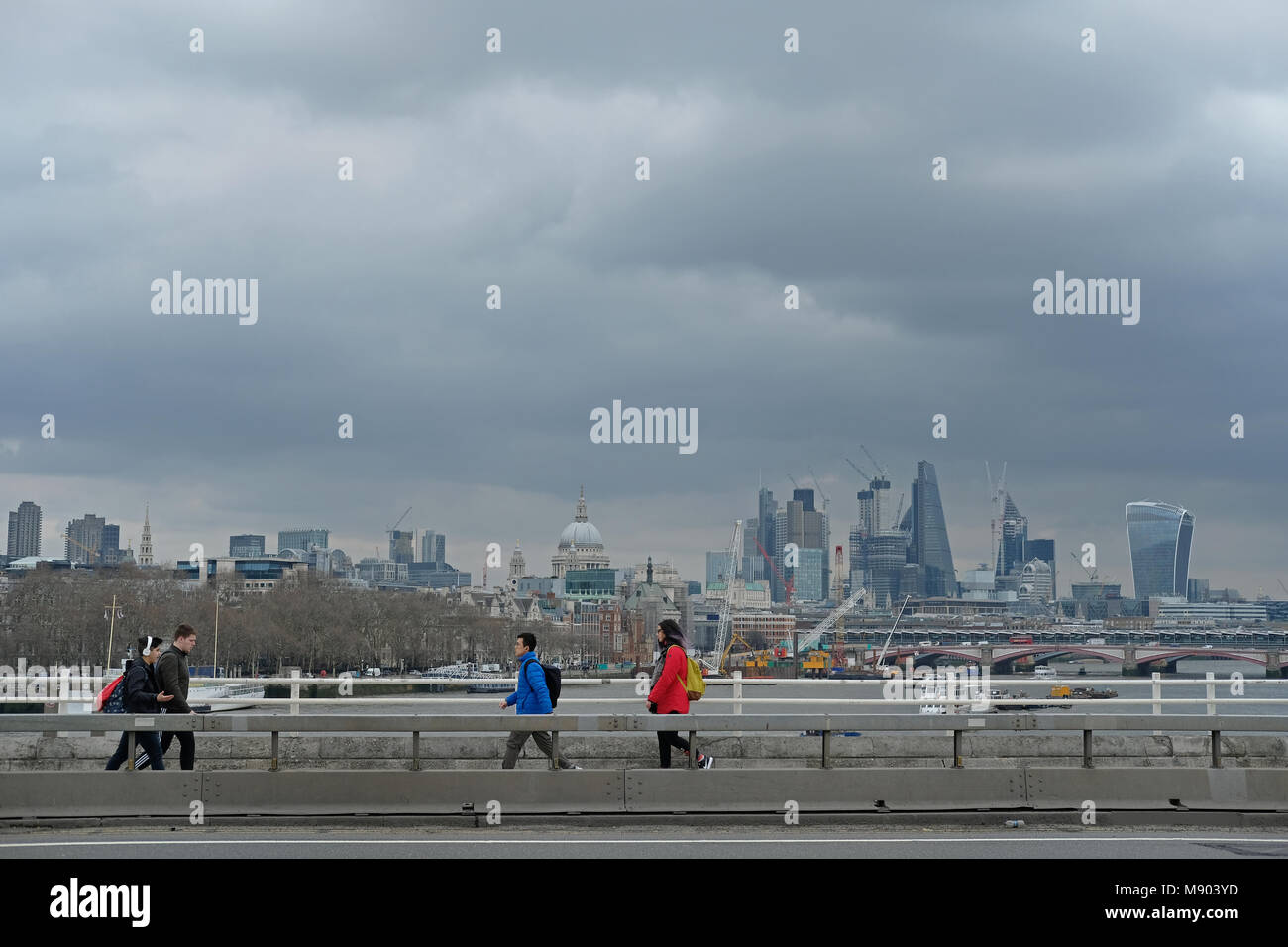 People cross Waterloo bridge on a cloudy day. Stock Photo