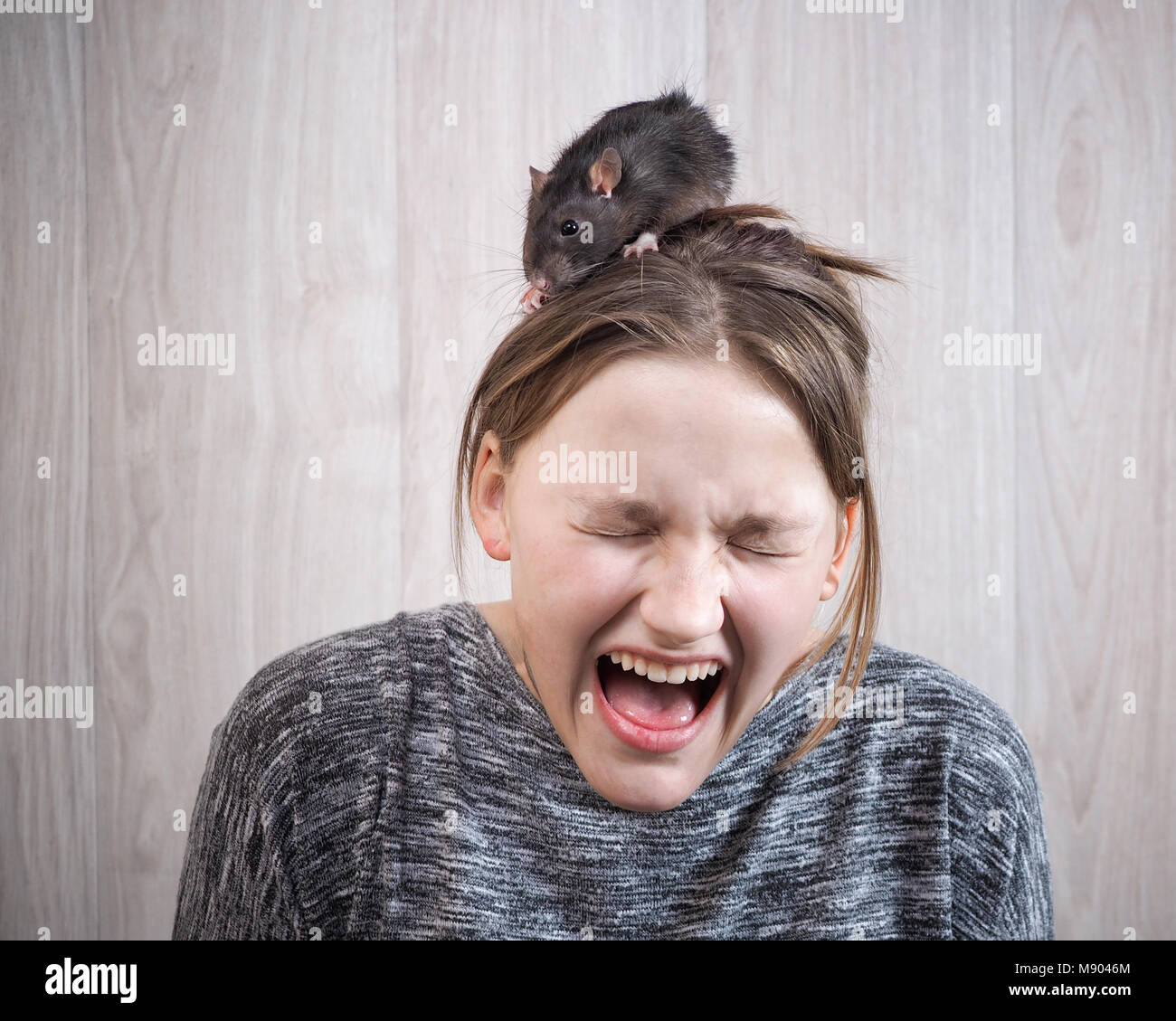 The girl in panic shouting. On her head sits a rat. The concept of a phobia, a fear of rodents