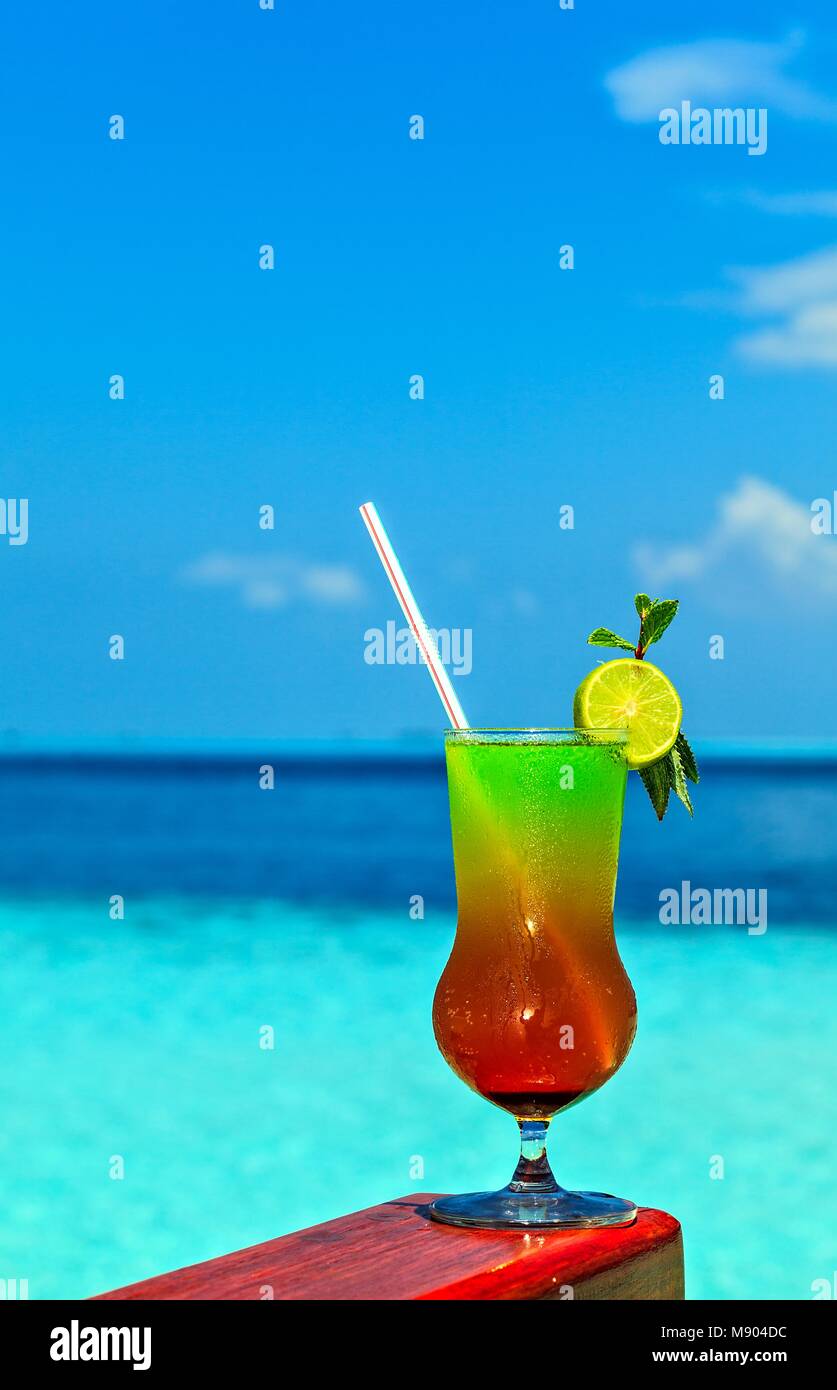 Glass of the soft drink is on a beach table (Maldives, The Indian Ocean
