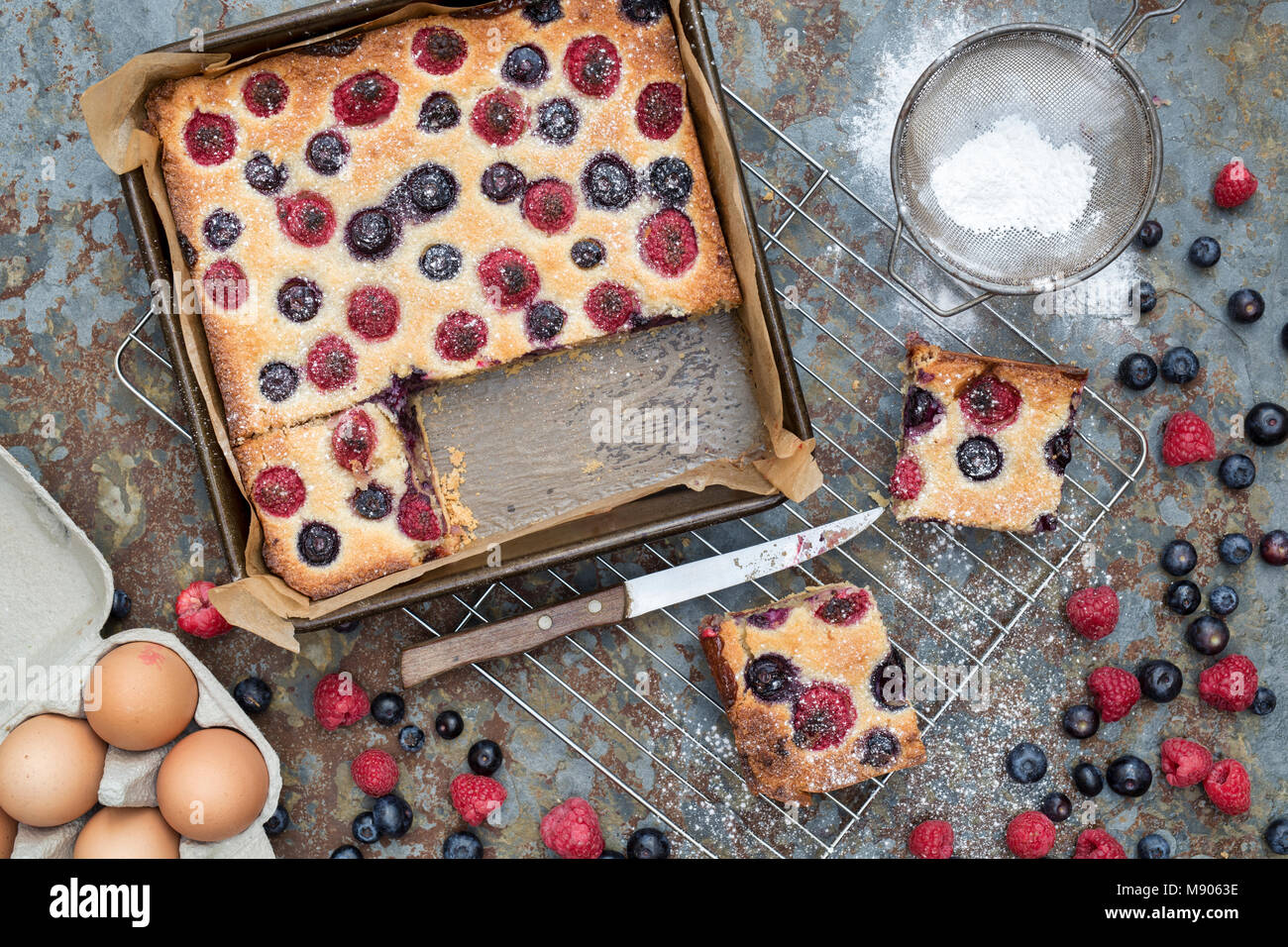 Homemade raspberry and blueberry frangipane tart with ingredients on a slate background Stock Photo