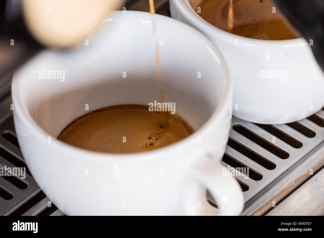 Two espresso cups getting filled in a portafilter machine Stock Photo -  Alamy