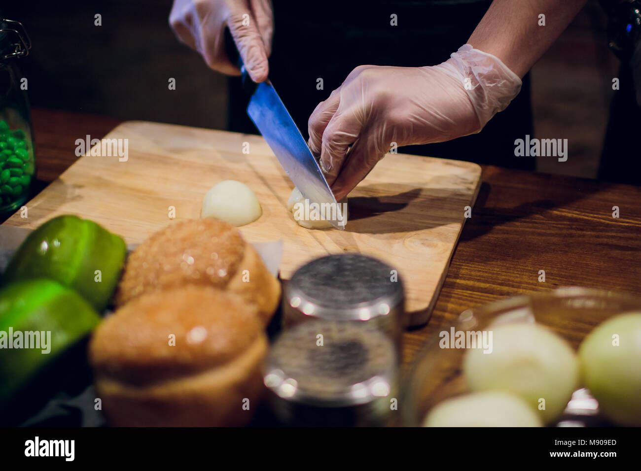 Chef's hands with knife cutting the onion on the wooden board ...