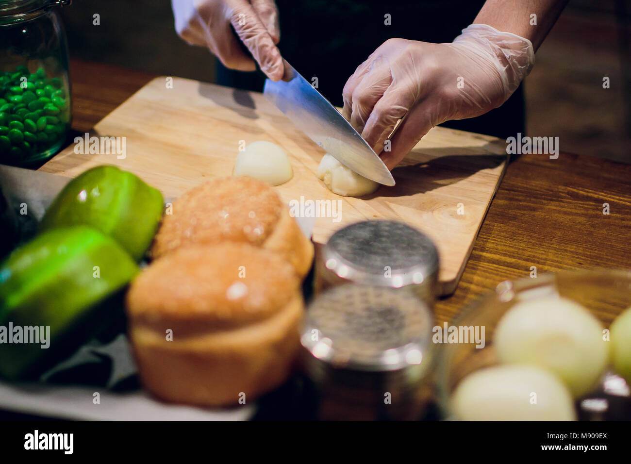 Chef's hands with knife cutting the onion on the wooden board ...