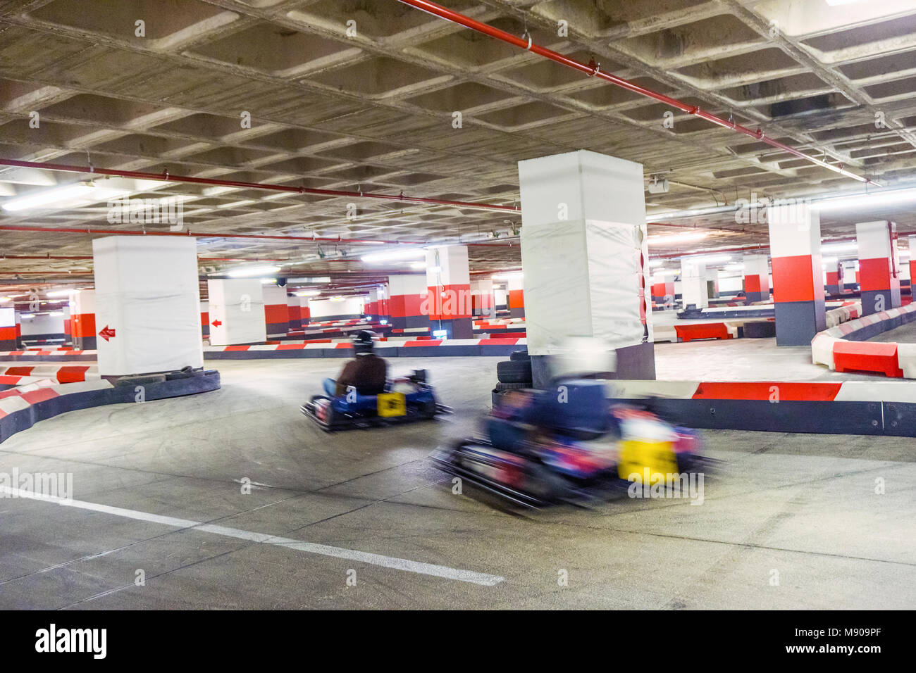 Two people racing on indoor karting track located in underground parking lot Stock Photo