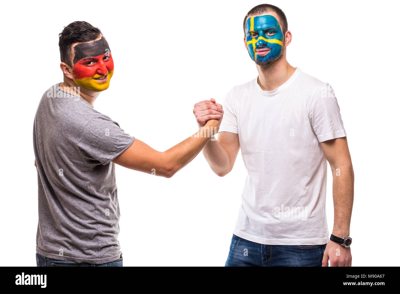 Handsome men supporters loyal fans of Sweden national team And Germany with painted flag face handshake on white. Stock Photo
