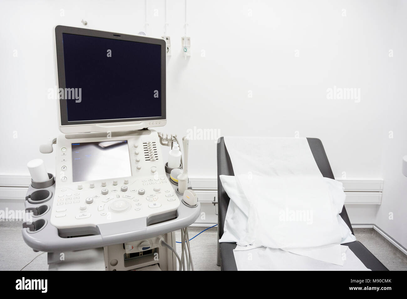 Black bed and white pillow next to ultrasound in white hospital room Stock Photo