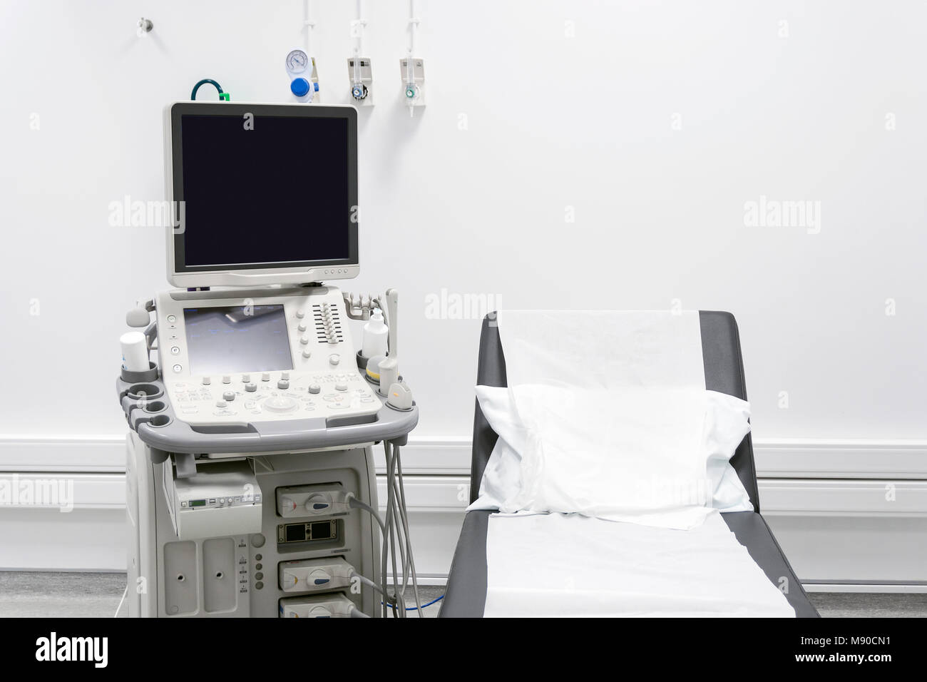 Black bed and white pillow next to ultrasound in white hospital room Stock Photo