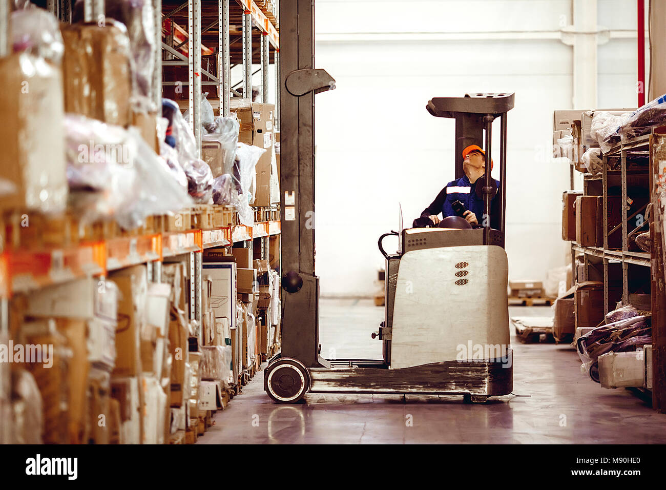 Man on lift operator in uniform at warehouse Stock Photo