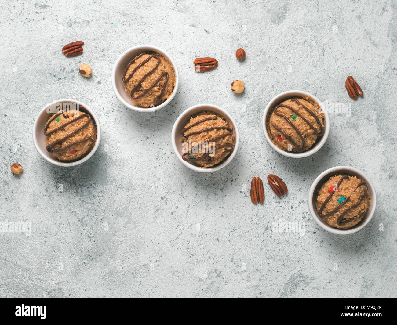 Safe-to-eat raw monster cookie dough in small portion bowl on gray cement background. Ideas and recipes for kids and toddlers meal. Top view or flat-lay. Copy space for text. Stock Photo