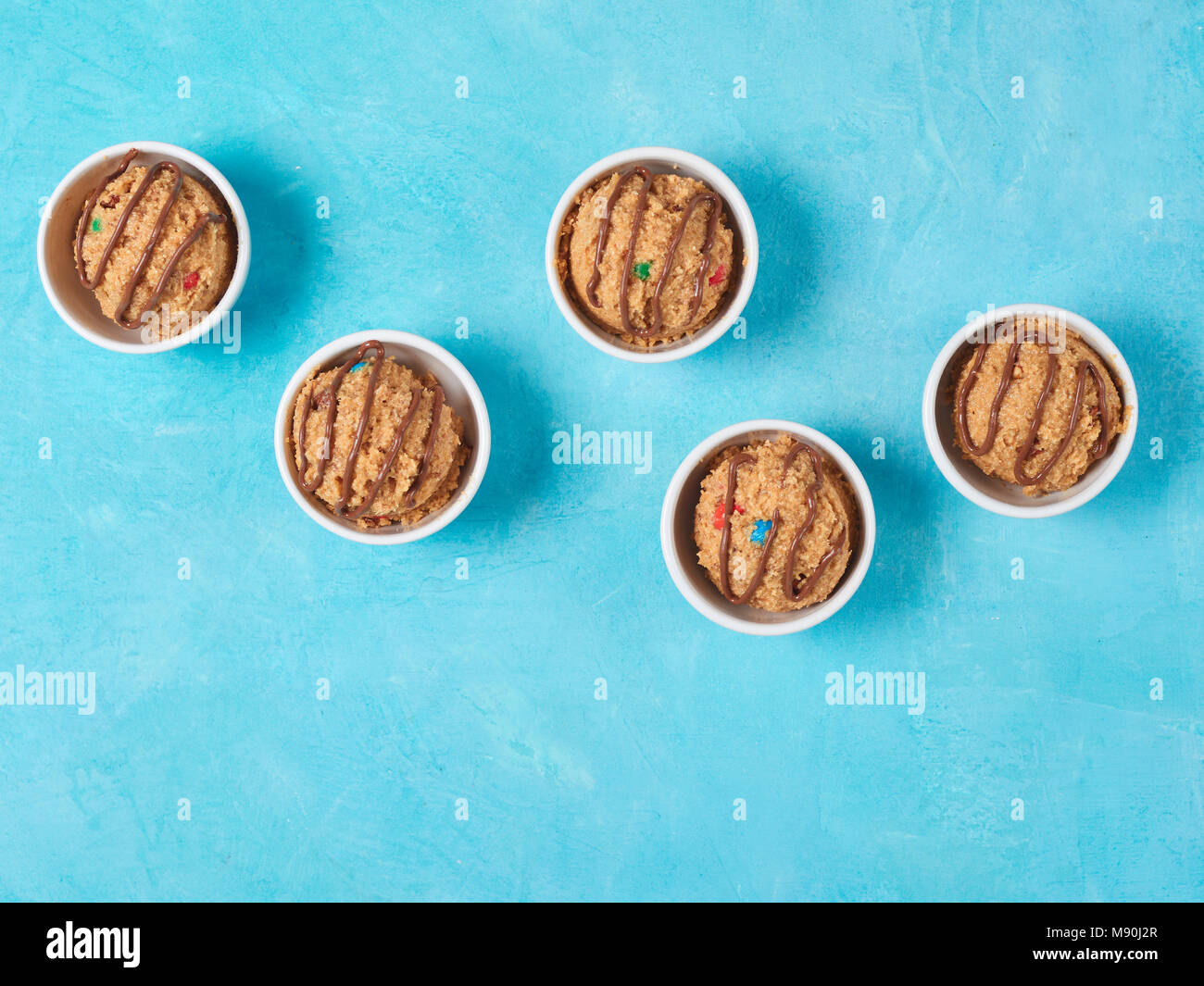 Safe-to-eat raw monster cookie dough in small portion bowl on blue background. Ideas and recipes for kids and toddlers meal. Top view or flat-lay. Copy space for text. Stock Photo